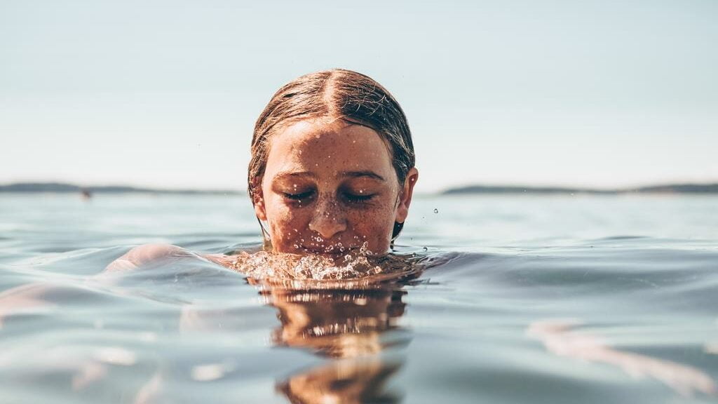 Mulher de olhos fechados e a cabeça para fora água