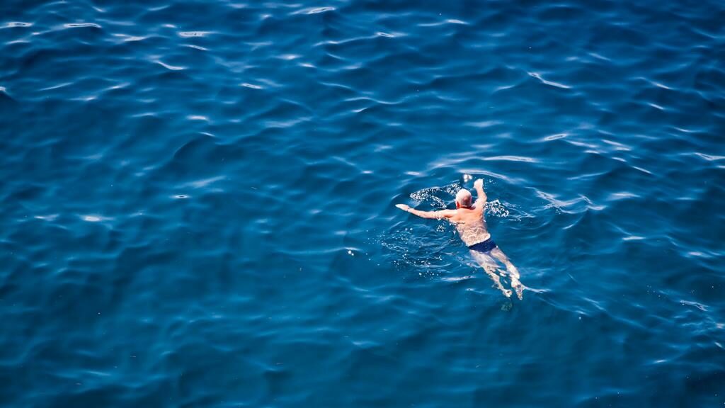 senhor nadando no mar