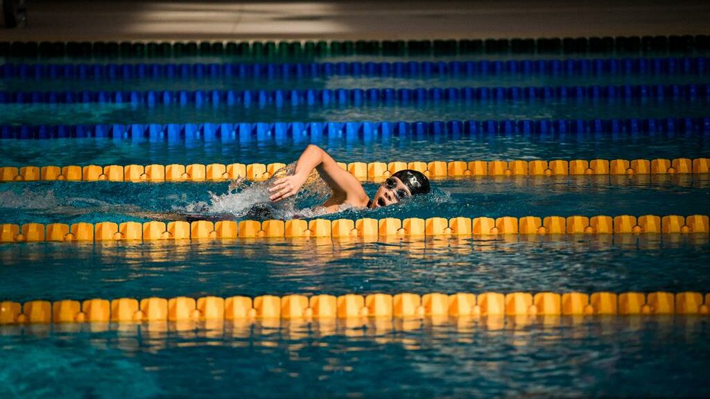atleta nadando em piscinas com raias amarelas e azuis