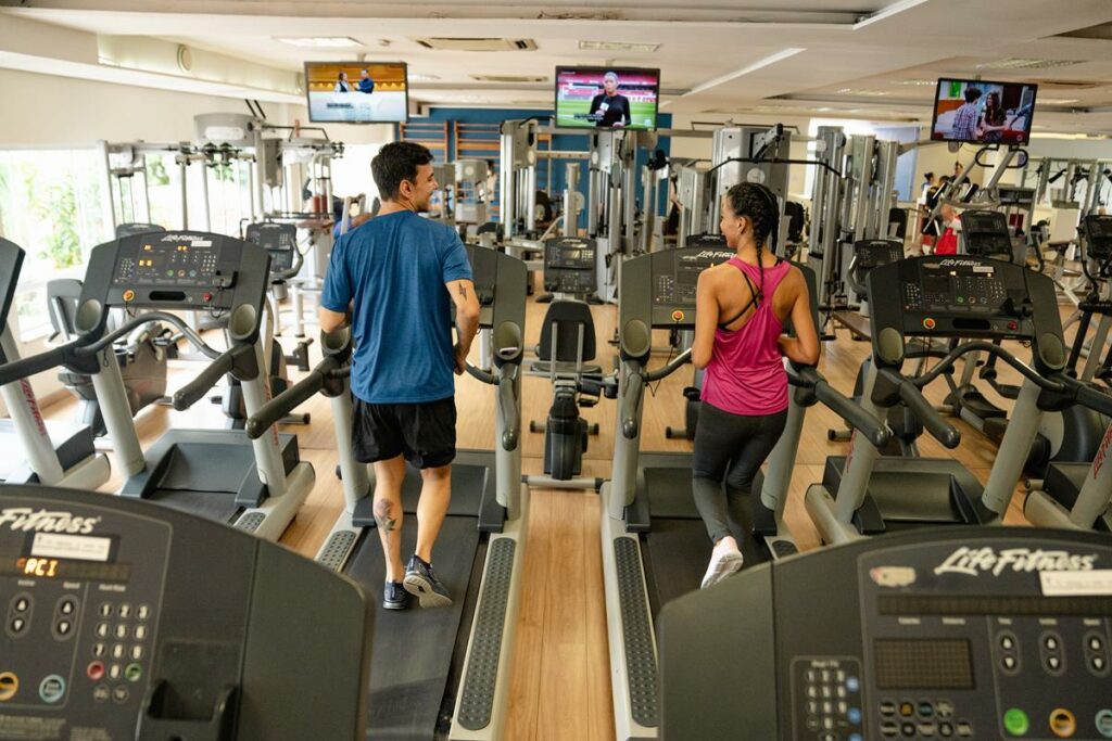 homem e mulher caminhando na esteira em academia com roupas fitness Oxer