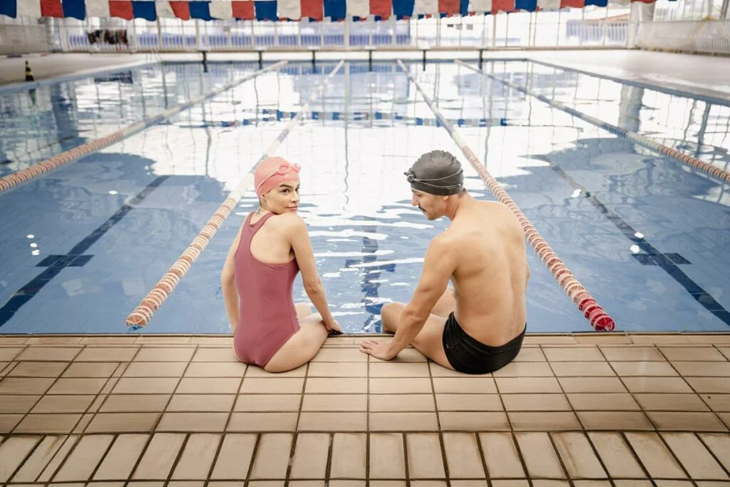 homem e mulher sentado na beira da piscina