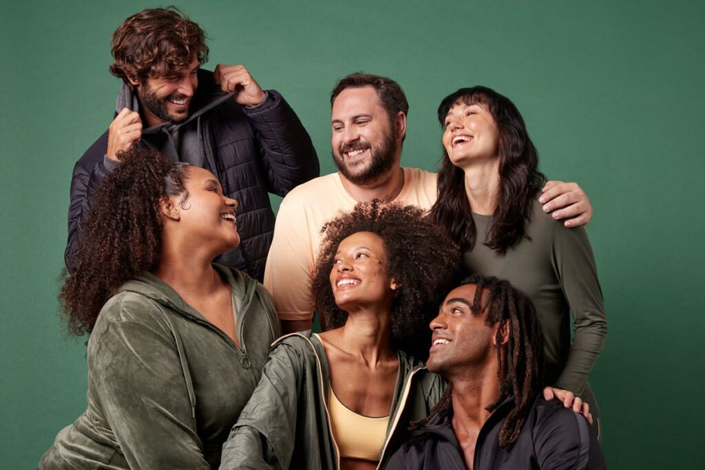 seis pessoas usando vestuário da coleção de inverno 2023 da Oxer Brasil em fundo verde