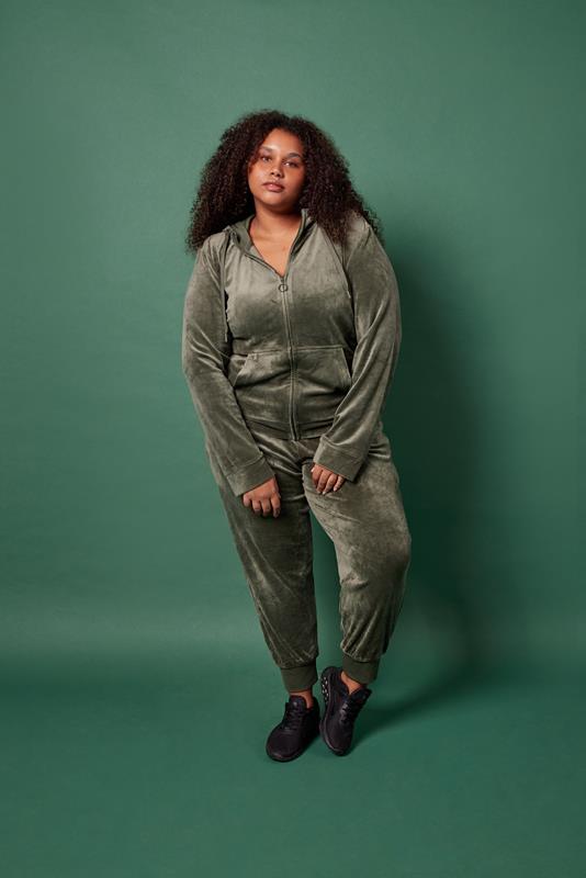 mulher usando vestuário da coleção de inverno 2023 da Oxer Brasil em fundo verde