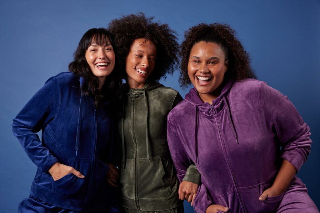 três mulheres usando vestuário da coleção de inverno 2023 da Oxer Brasil em fundo azul