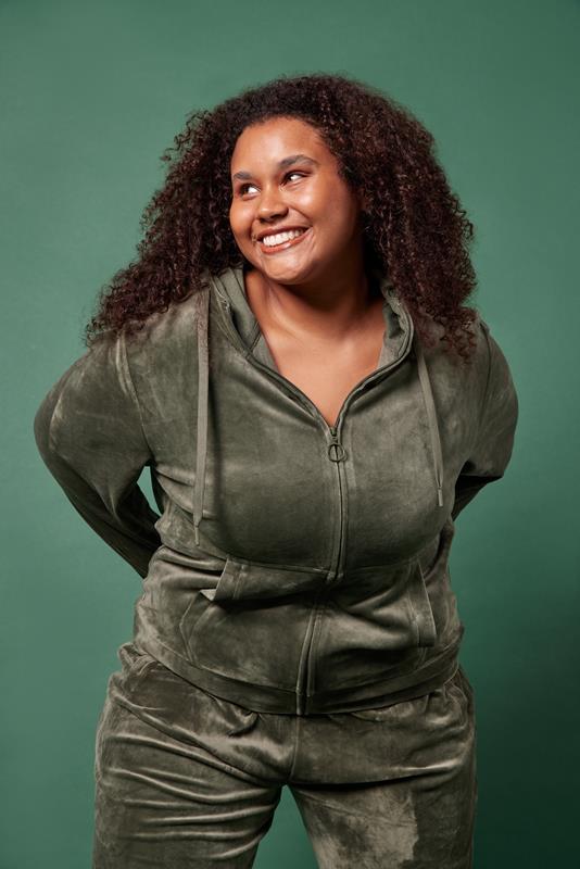 mulher usando vestuário da coleção de inverno 2023 da Oxer Brasil em fundo verde