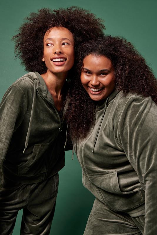 duas mulheres usando vestuário da coleção de inverno 2023 da Oxer Brasil em fundo verde