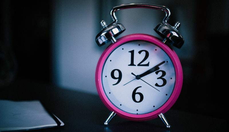 Power nap. Foto de um relógio de mesa na cor rosa com detalhes branco e prata